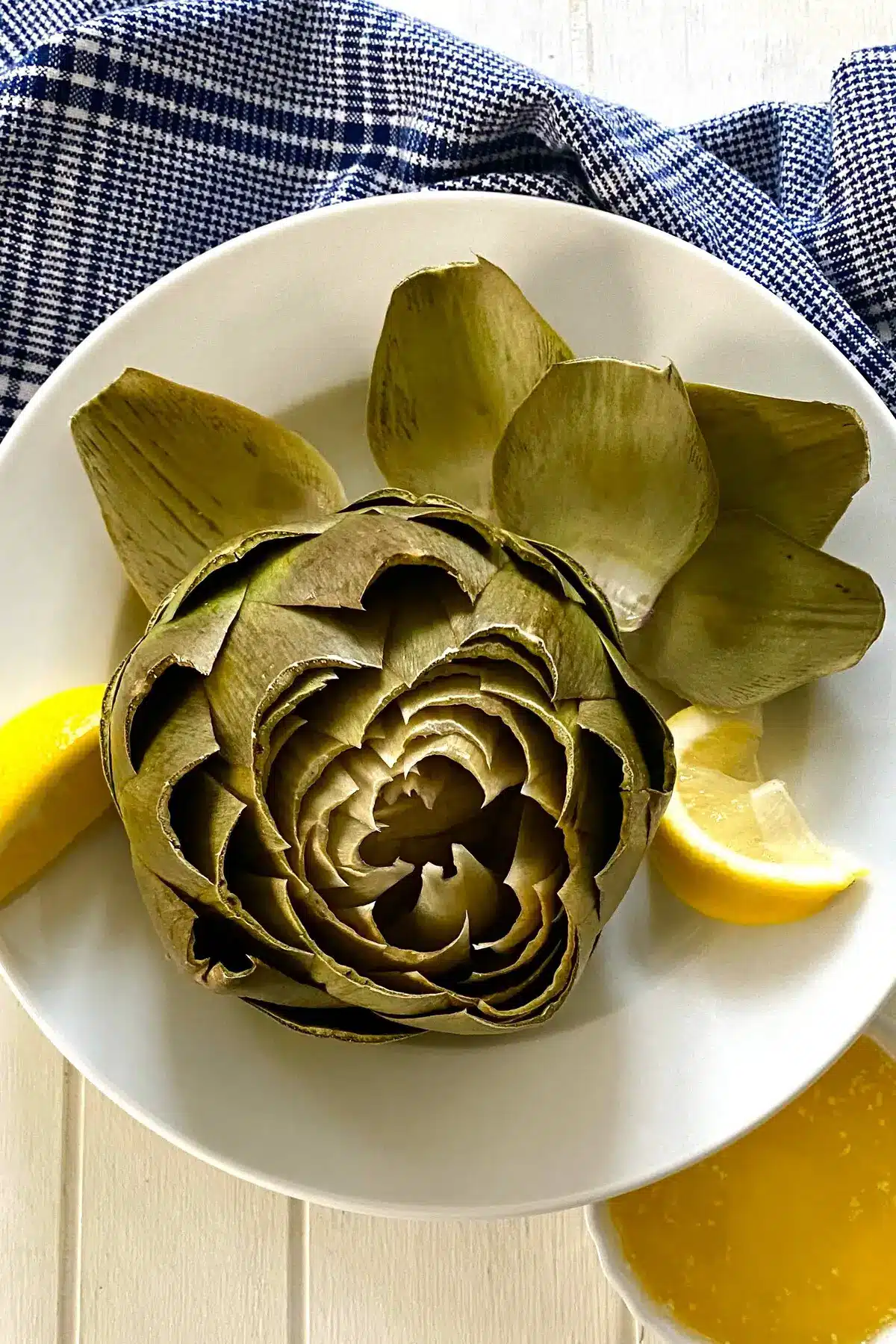 a cooked artichoke with lemon and some leaves removed.
