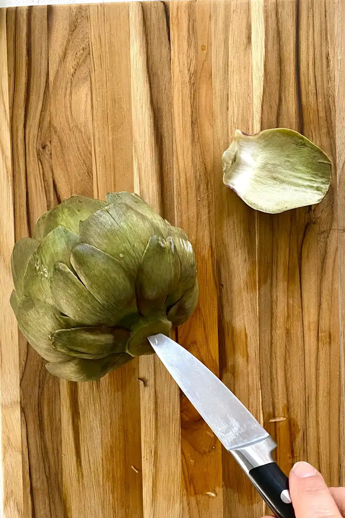 cooked artichoke on a cutting board.