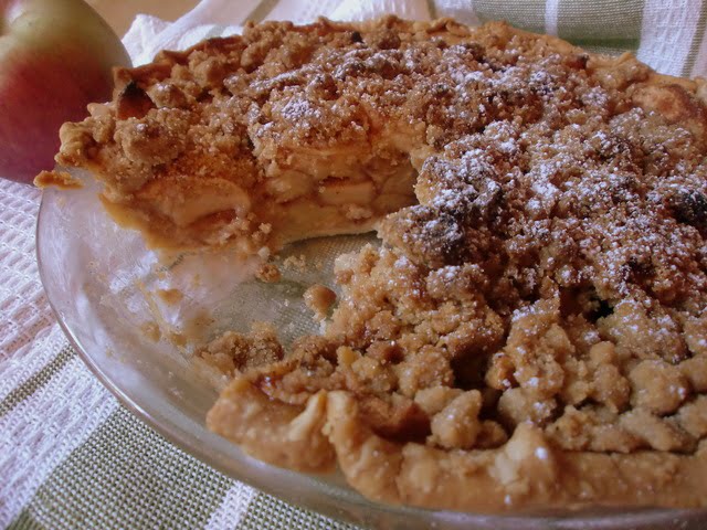 A apple crumb pie with a slice cut out of it.