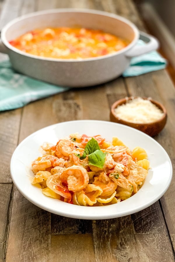 A bowl of shrimp with tomato sauce and a serving dish.