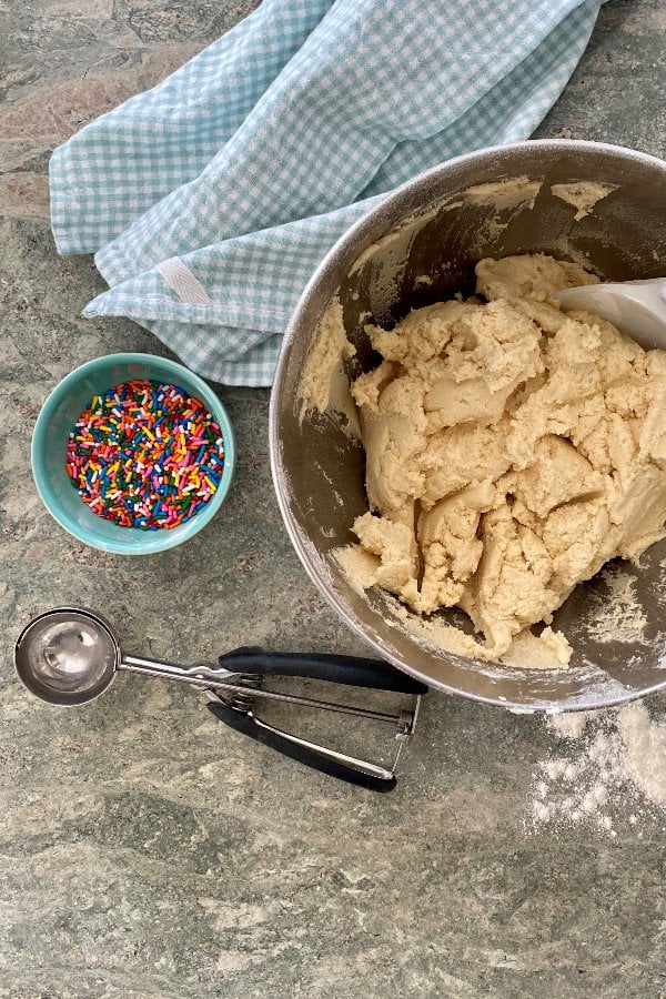 sugar cookie dough, rainbow sprinkles and a cookie scoop