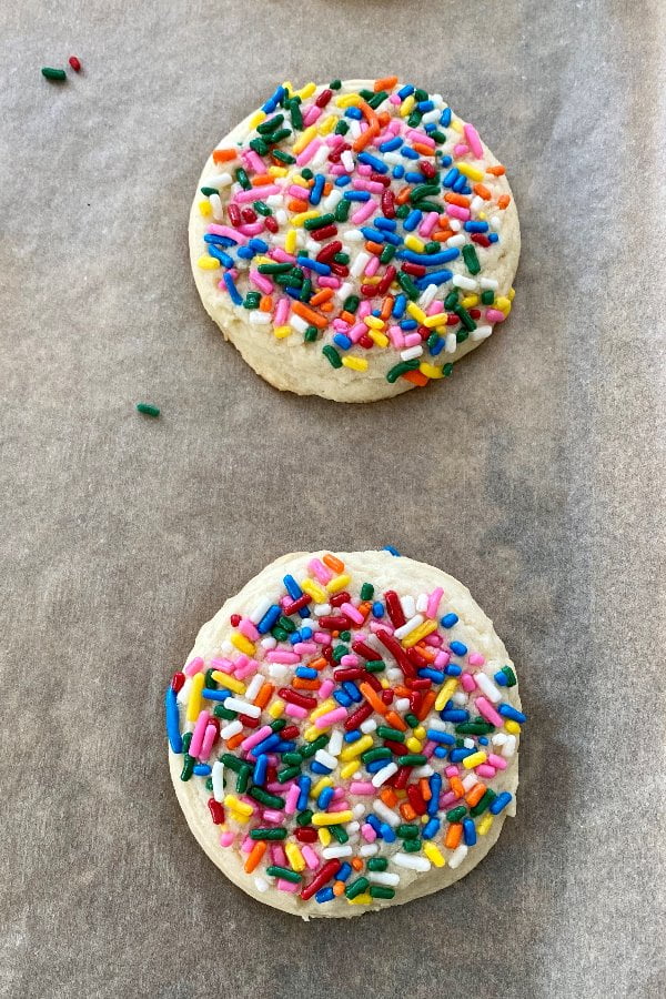 2 baked treats with rainbow sprinkles on parchment paper