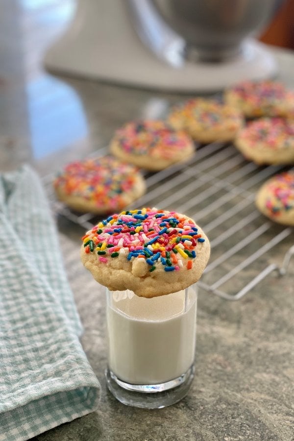 single sugar cookie on top of a glass of milk