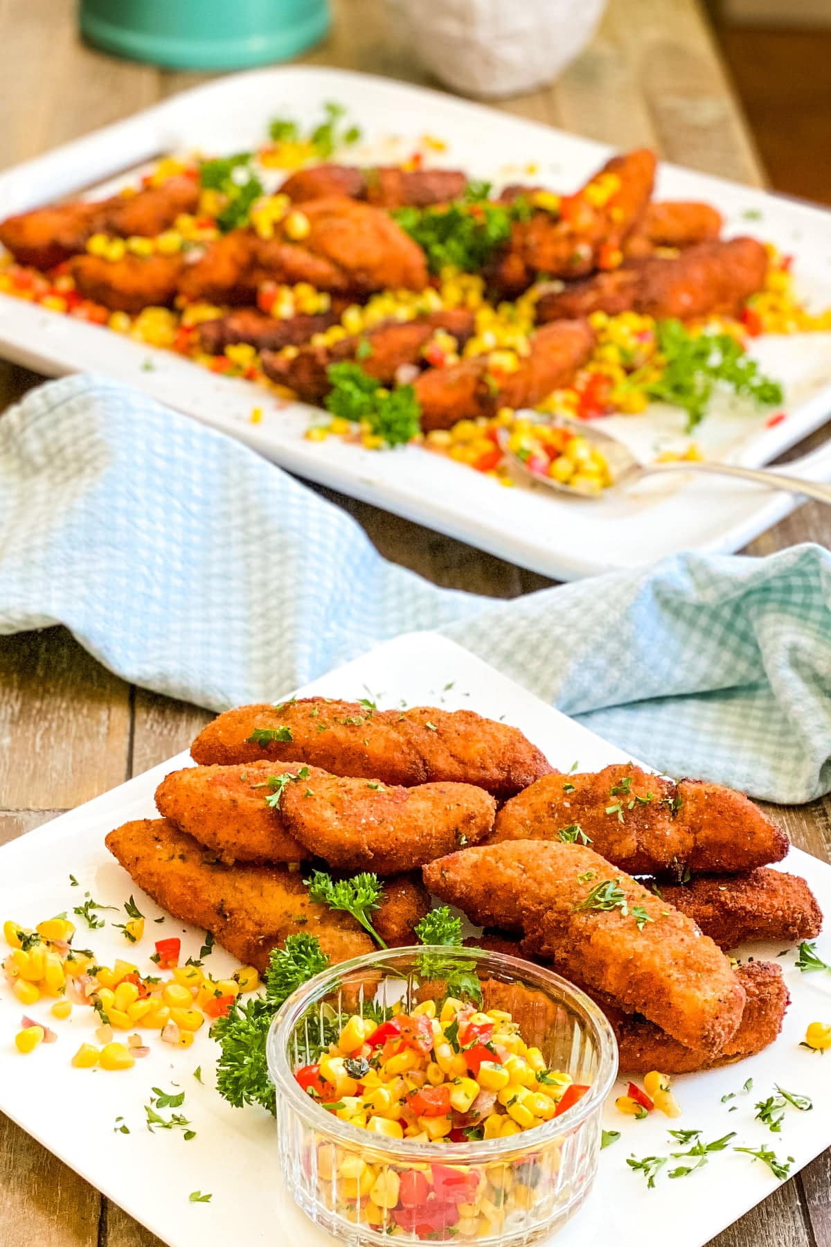 pan fried chicken tenders on a serving plate with fresh corn sauté