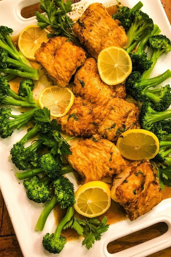 platter of fish cooked francese with lemons and broccoli