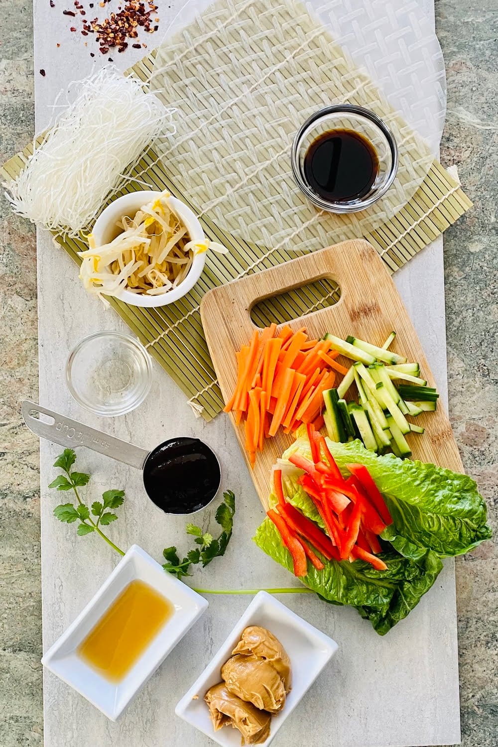 Bean sprouts, spring roll wrappers, carrots, cucumbers lettuce on a rolling mat.