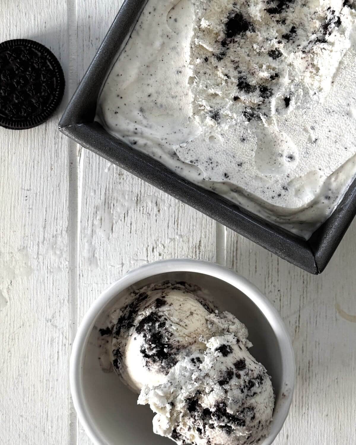 A bowl of cookies and cream and a frozen pan of ice cream.