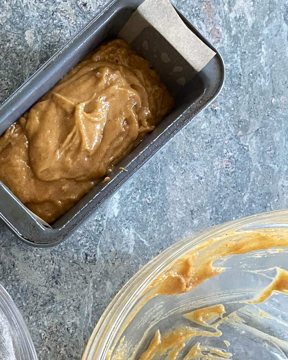 A mini loaf pan filled with pumpkin bread batter.