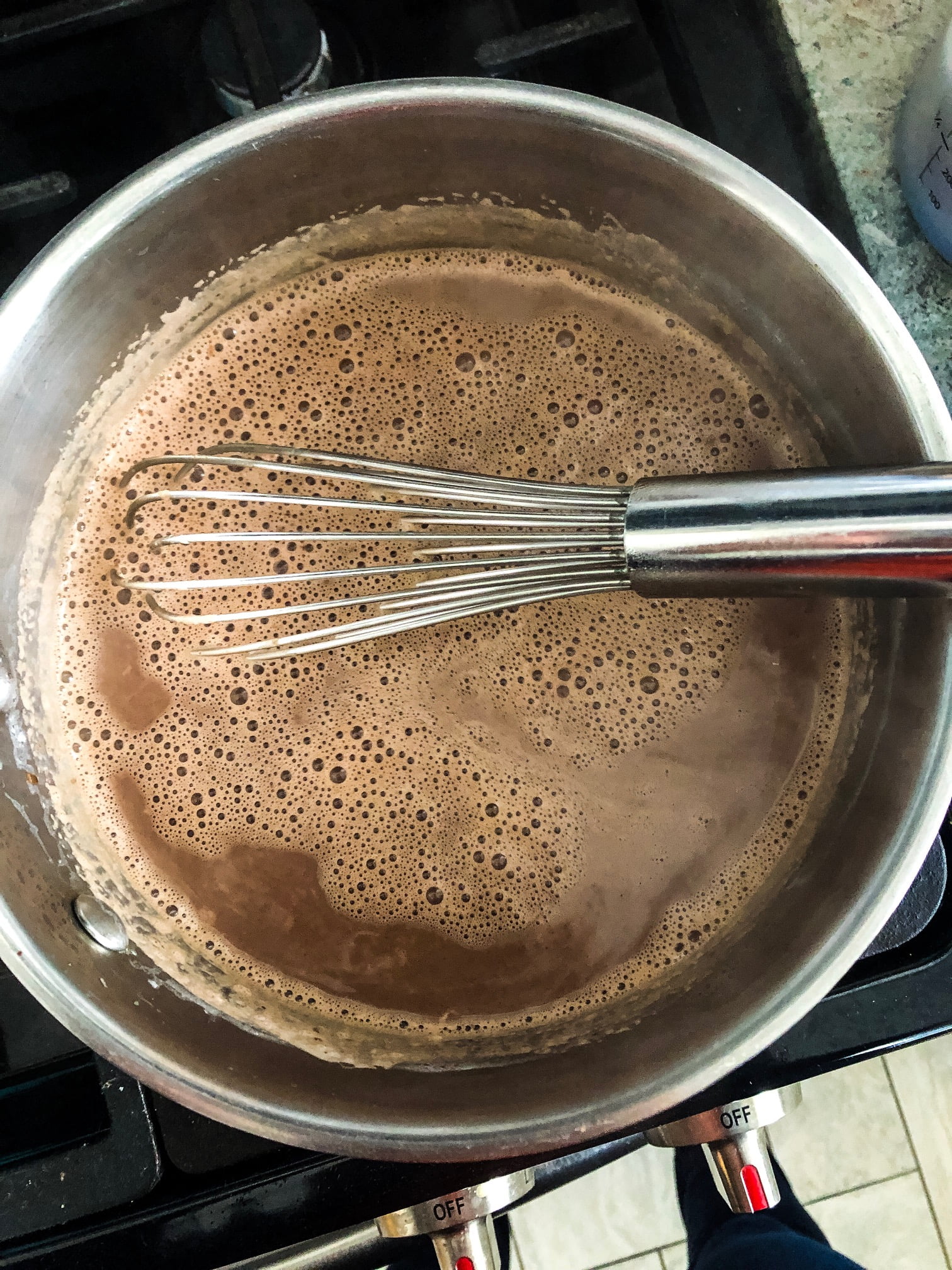 simmering pot of hot cocoa with a whisk