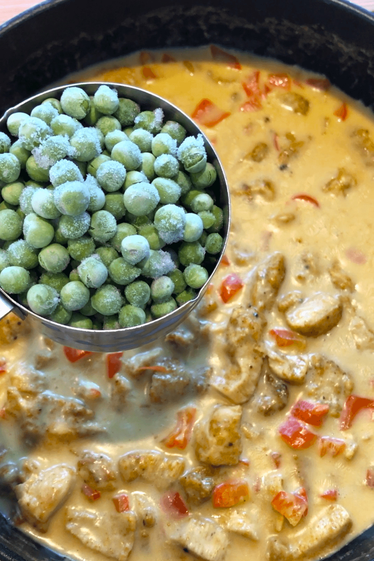 adding peas to Thai chicken recipe.