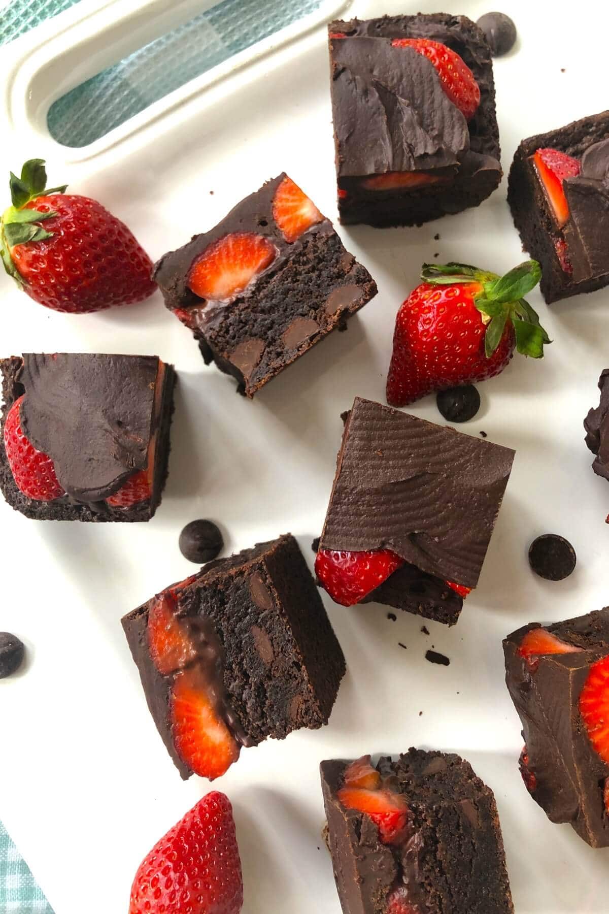A white plate with cut brownies with strawberries.