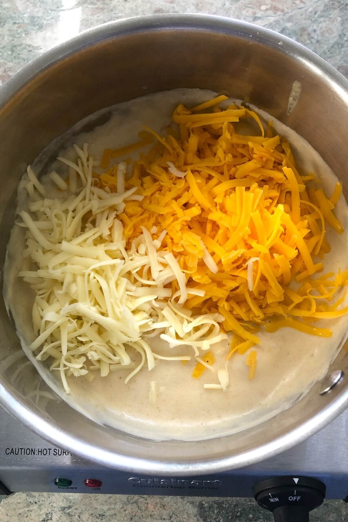 adding 2 kinds of cheese to a cheese sauce.