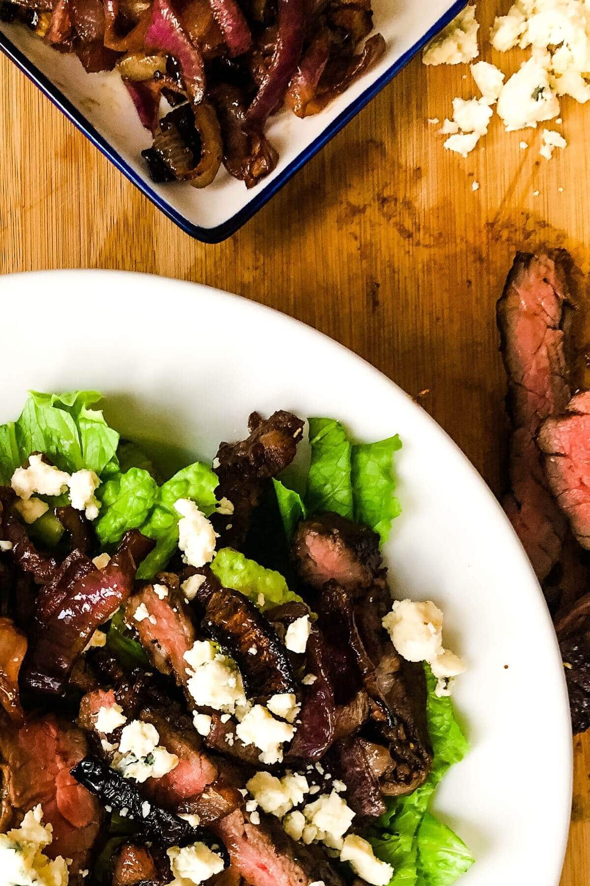 A closeup of a grilled steak salad over lettuce.