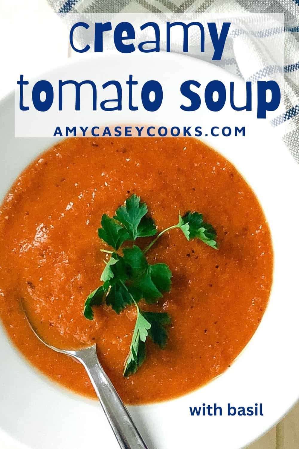 creamy roasted tomato basil soup in a bowl with a spoon and parsley.