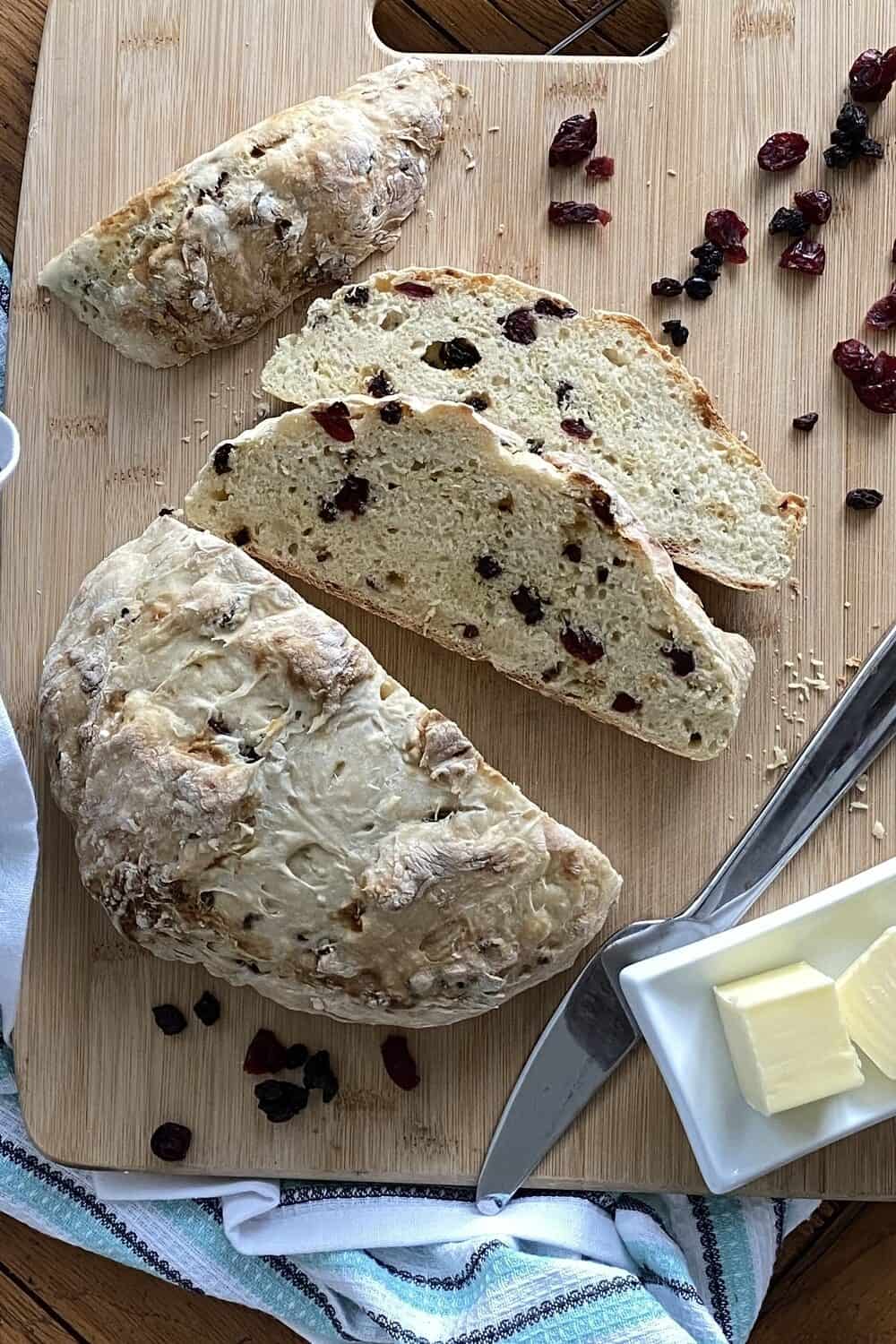 A loaf of soda bread and 2 slices on a cutting board.