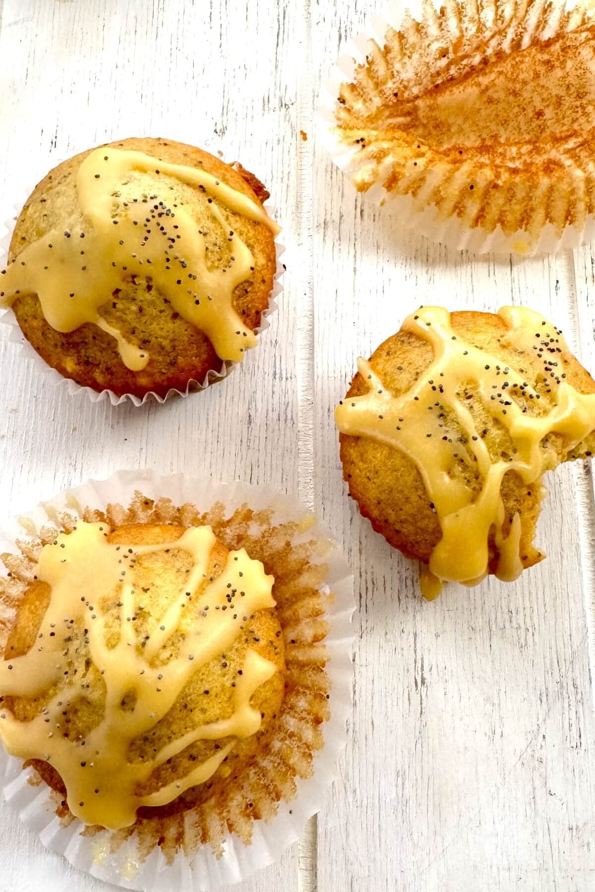 4 muffins with glaze and 1 muffin with a bite out of it.