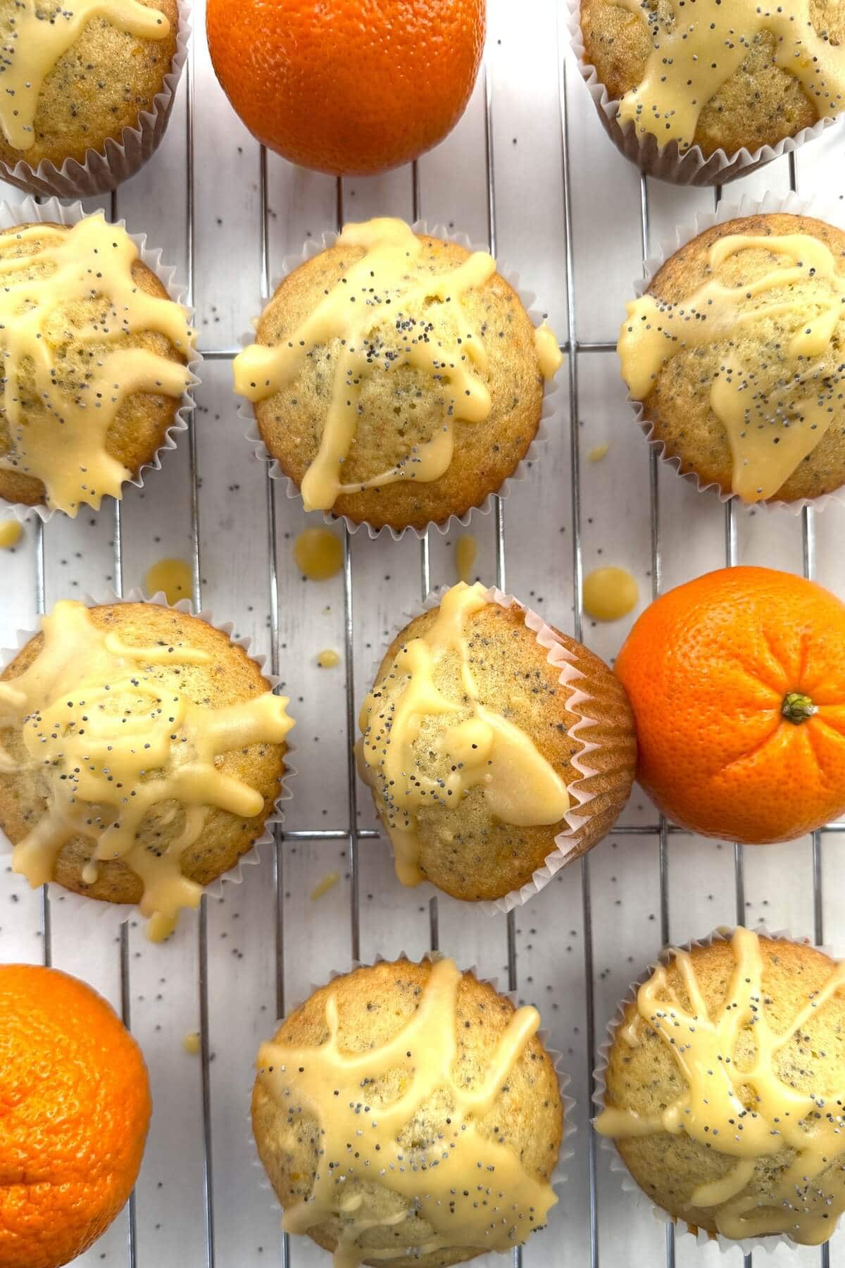 A cooling rack with muffins and oranges.