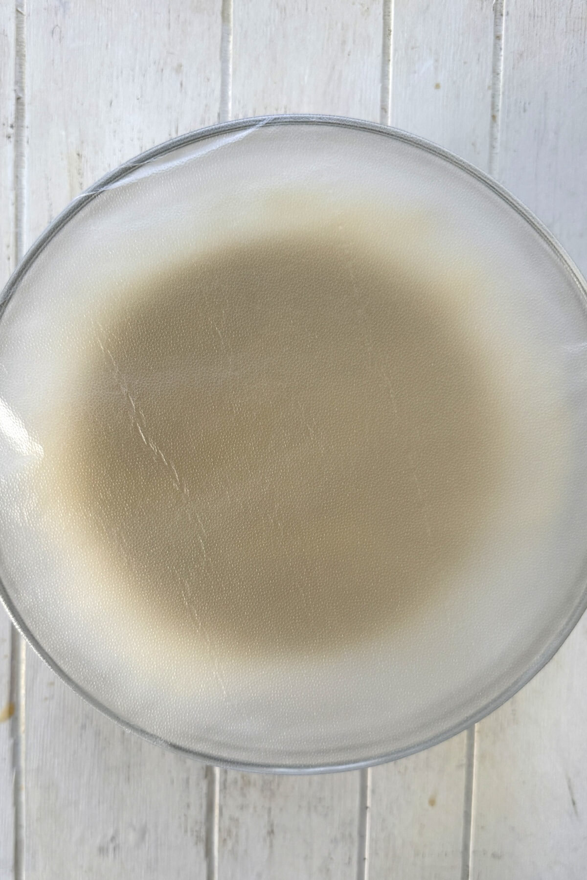 Plastic wrap covered bowl with muffin batter.