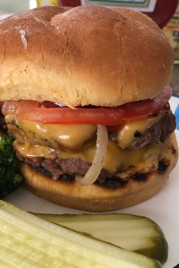 smash burger with sliced tomato and pickles