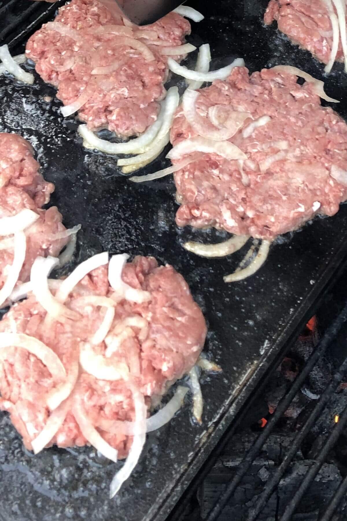 raw smash burgers on griddle.