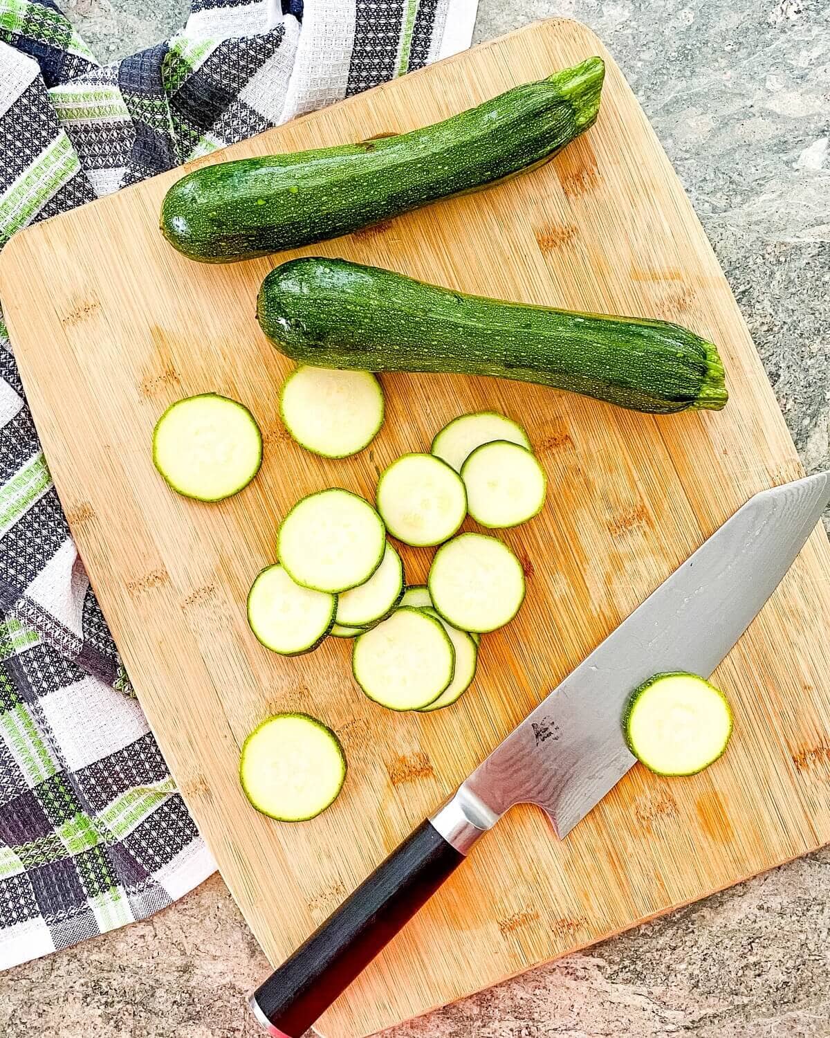 sliced and whole zucchini on a cutting board.