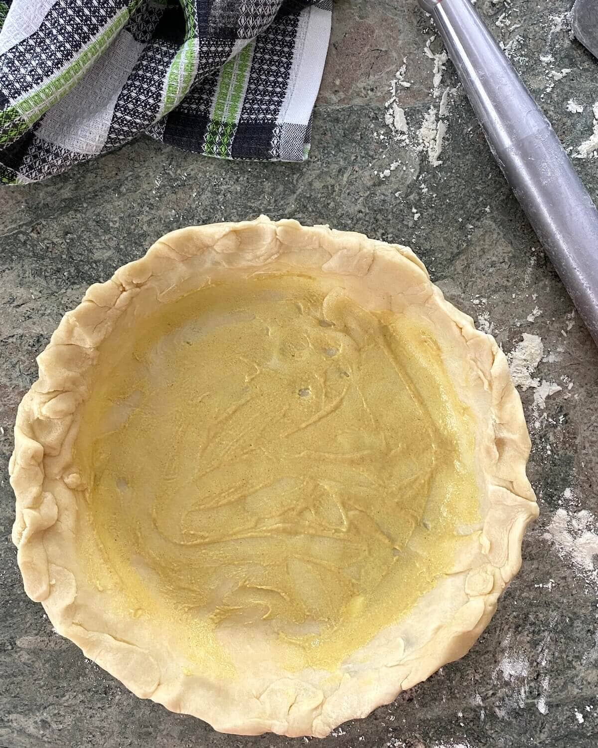 unbaked pie crust brushed with mustard.
