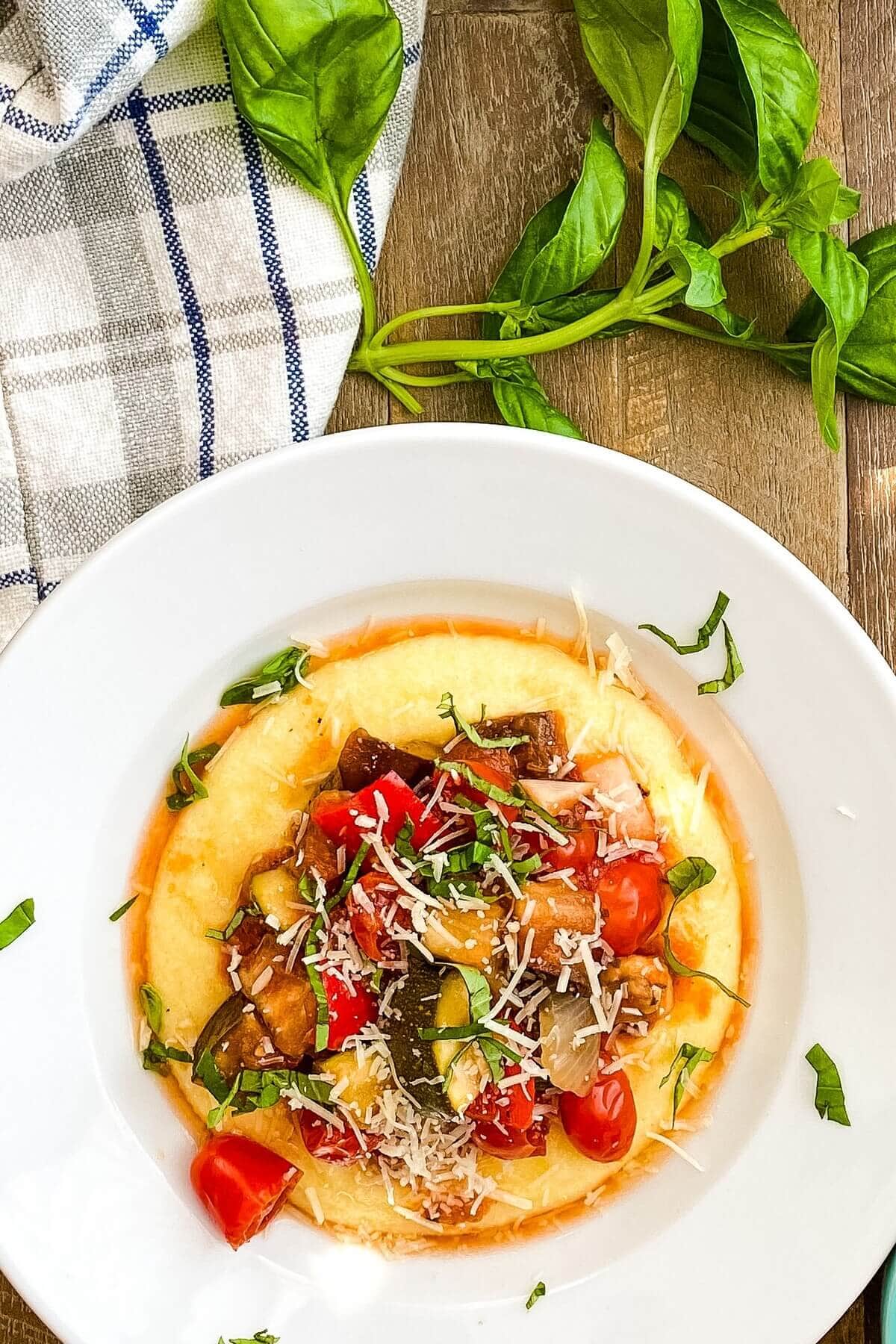 A bowl with polenta topped with ratatouille.