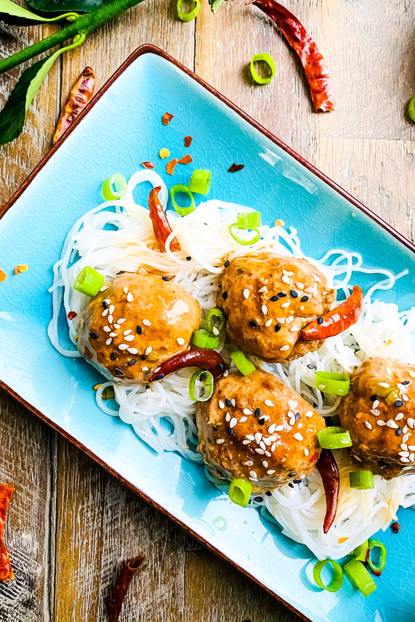 spicy meatballs with red chili peppers over rice noodles.