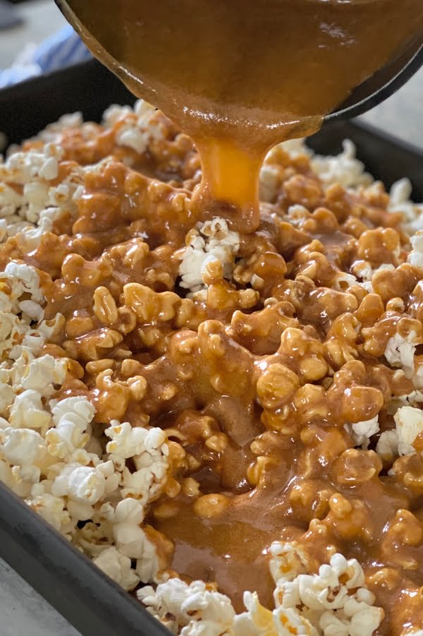 pouring sugary golden sauce over popped corn