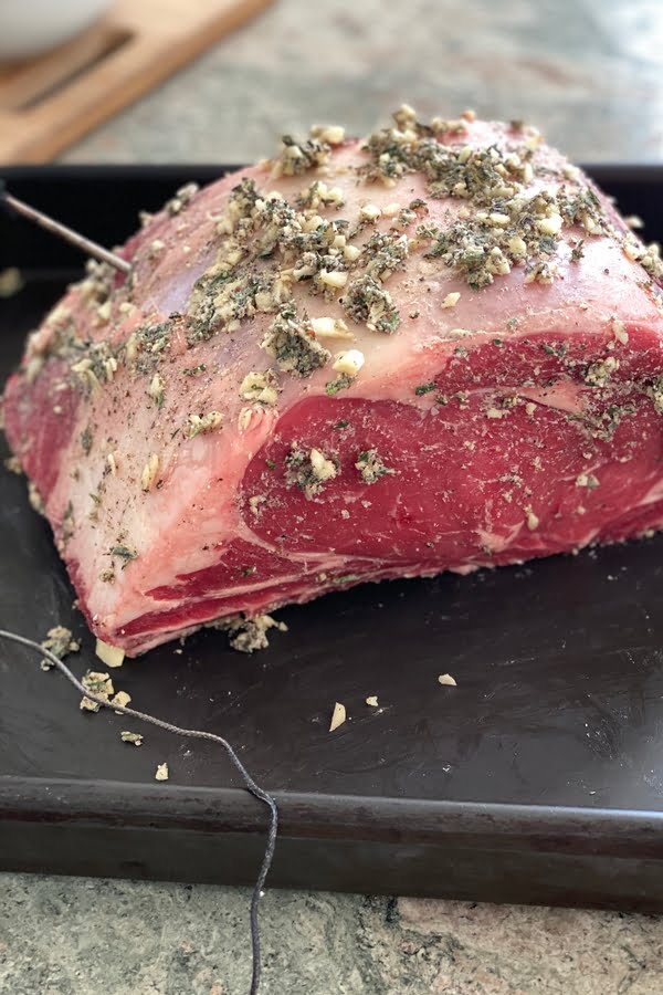 prime rib roast with butter, garlic, and herb rub with thermometer probes.