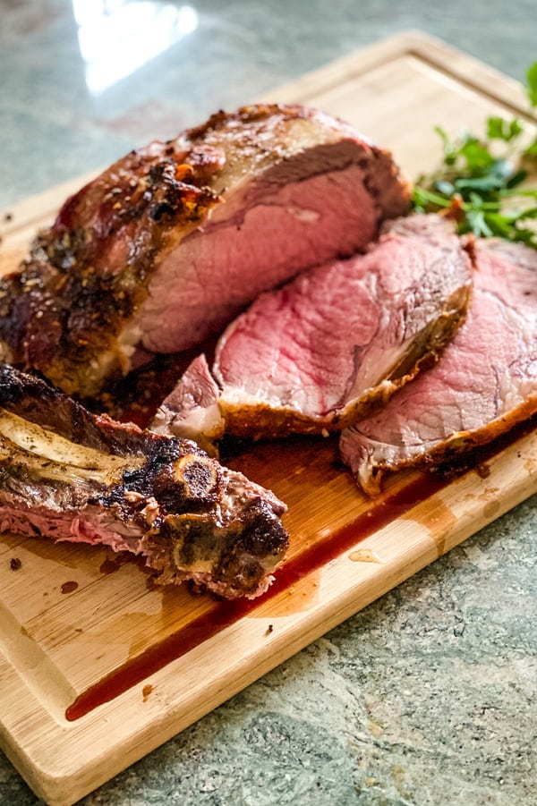 2 slices of slow roasted prime rib on a cutting board.