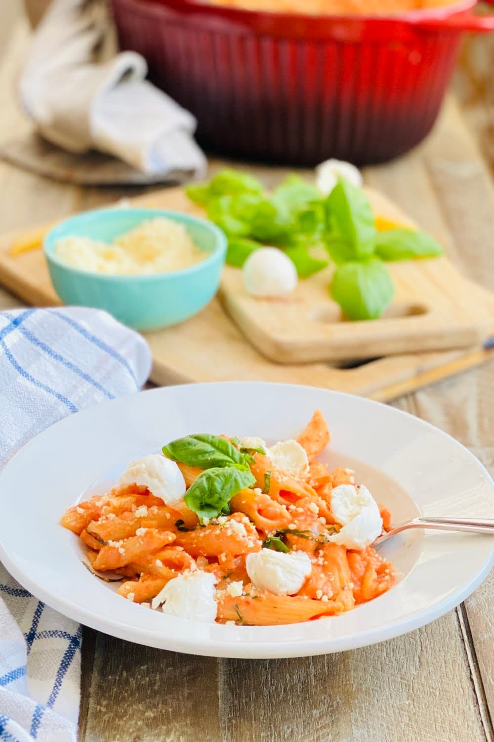 A bowl of pasta with fresh basil and mozzarella and parmesan.