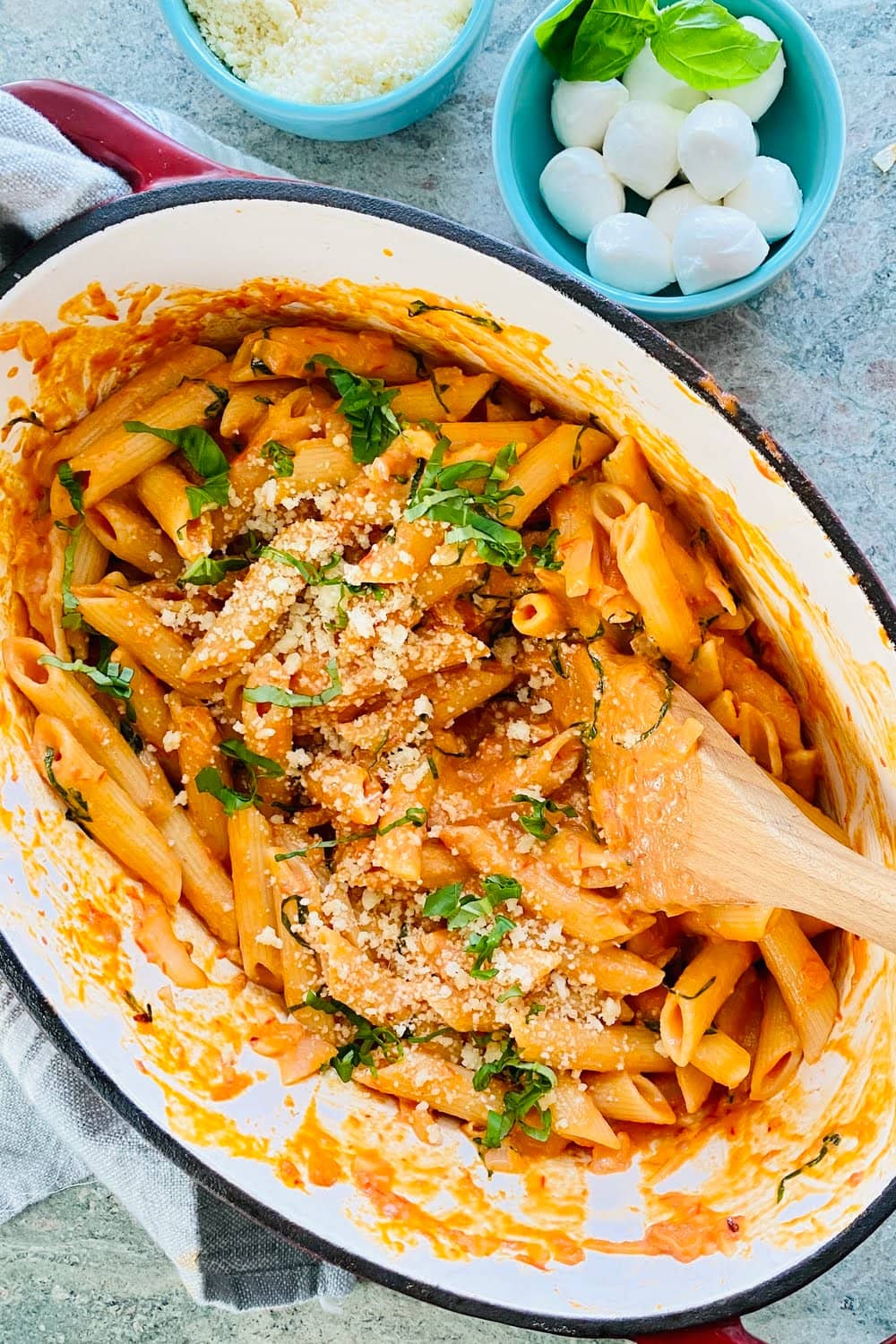 A large pot of pasta with fresh basil and Parmesan cheese.