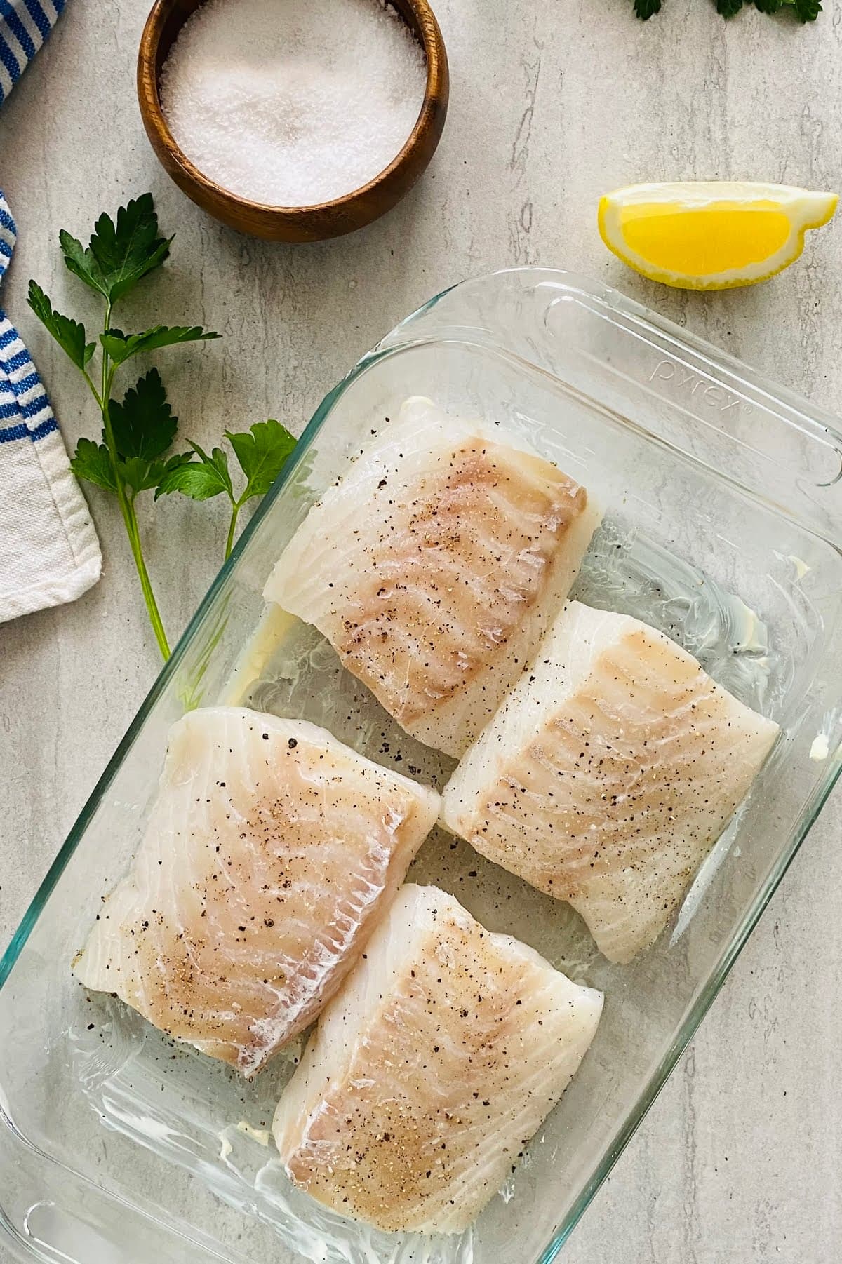 4 cod filets in a buttered baking dish and seasoned with salt and pepper.