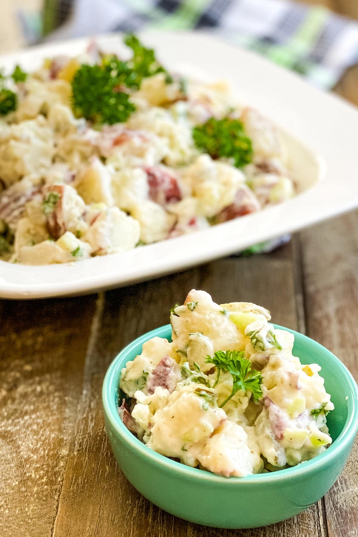 large bowl of creamy red potato salad with dill pickles and a small serving
