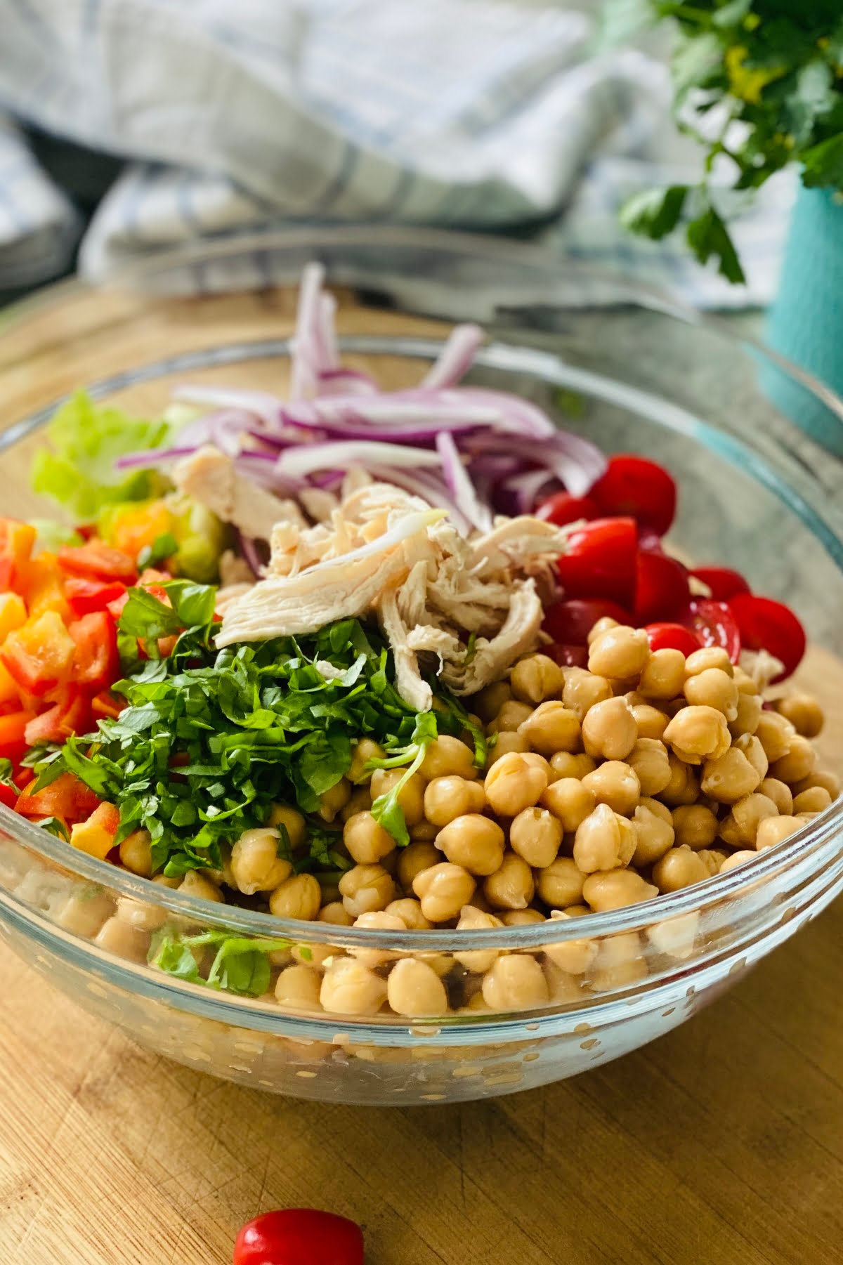 chickpeas, tomatoes, chicken, bell peppers, brussels sprout leaves in a large glass bowl