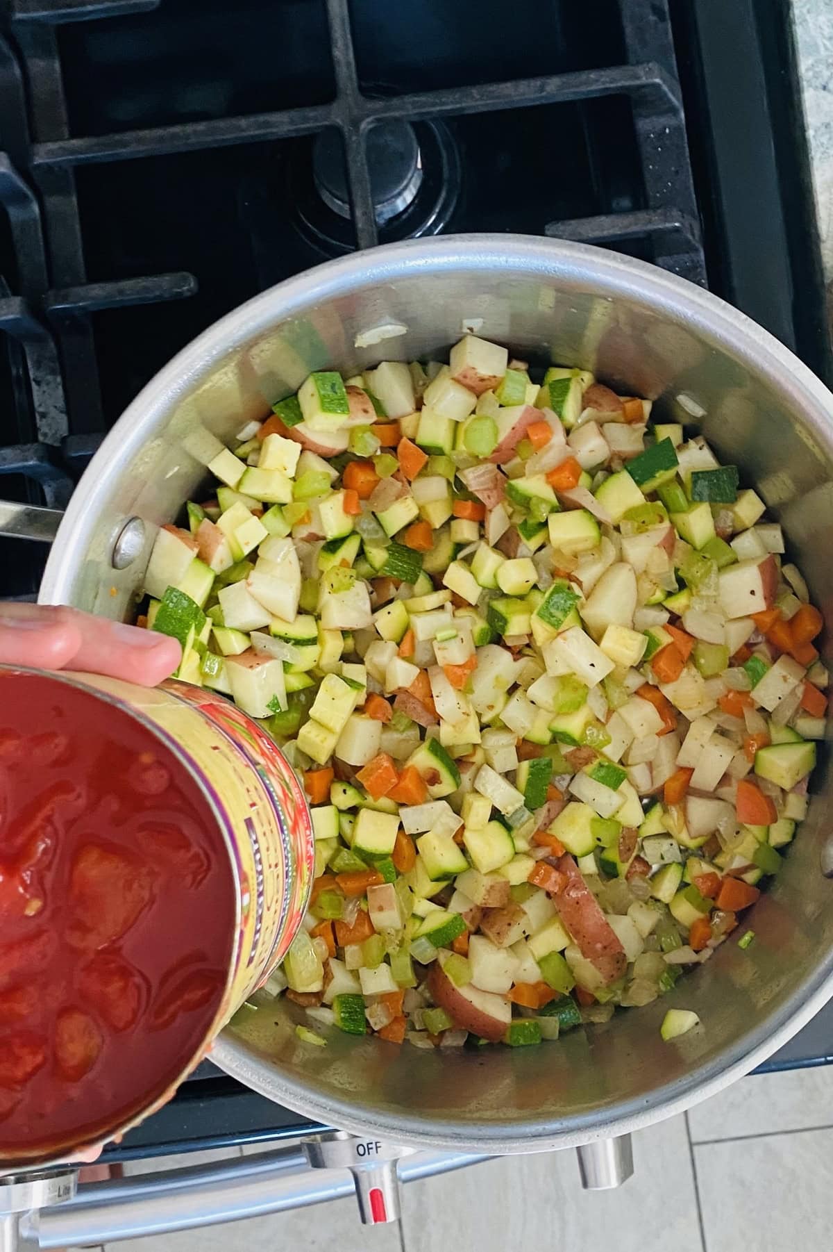 Adding crushed tomatoes to sautéed vegetables.