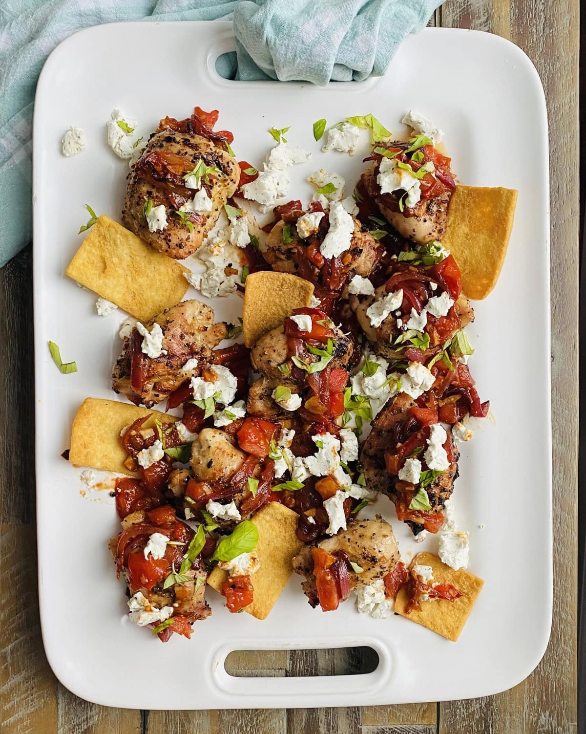 platter of grilled chicken thighs with sautéed bruschetta and goat cheese