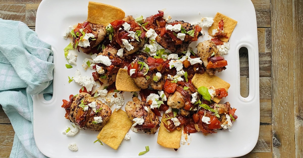 platter with grilled chicken thighs and sauteed tomatoes and goat cheese