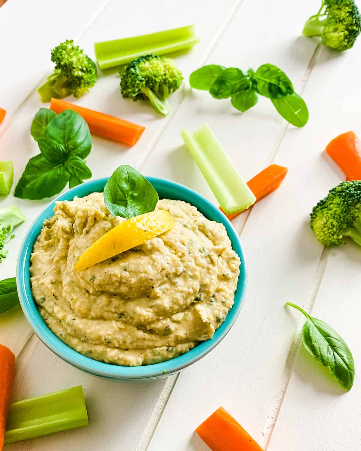 bowl of basil hummus with cut up vegetables