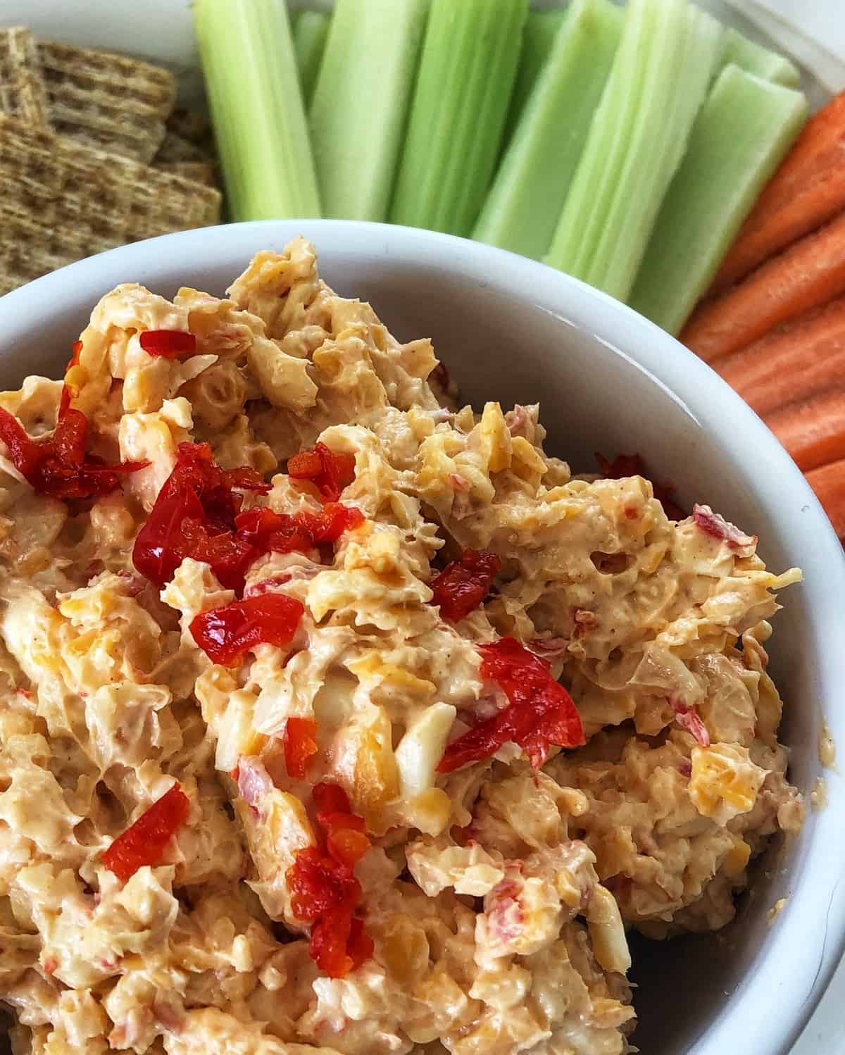bowl of pimento cheese with carrot and celery sticks and wheat crackers