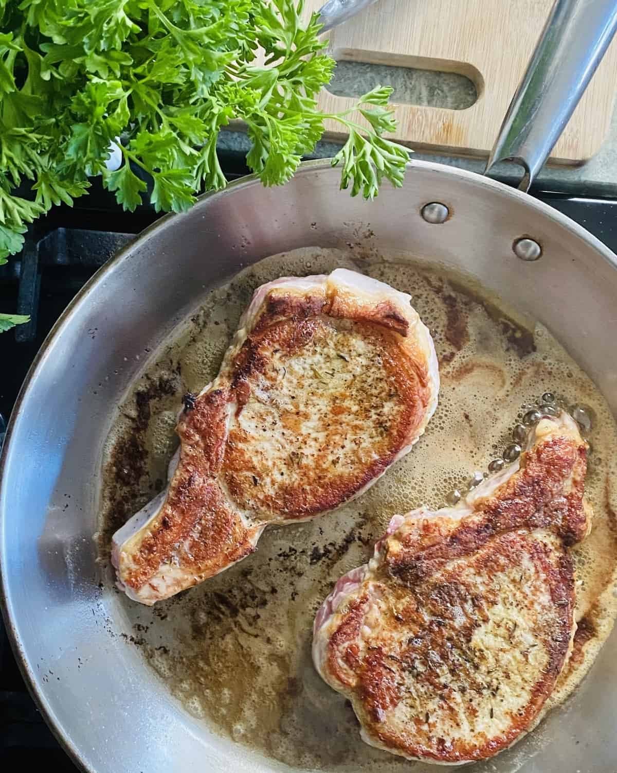 Searing pork chops in a sauté pan.
