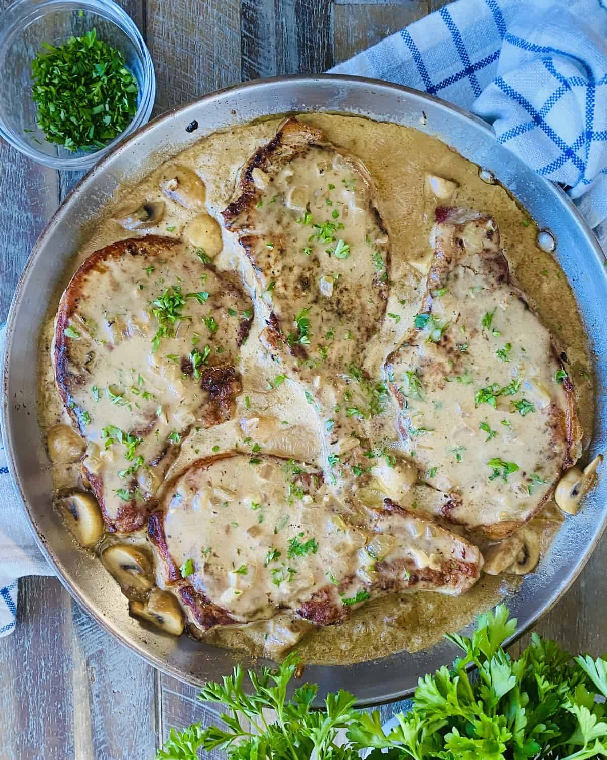 4 pork chops in a creamy mushroom gravy in a pan.