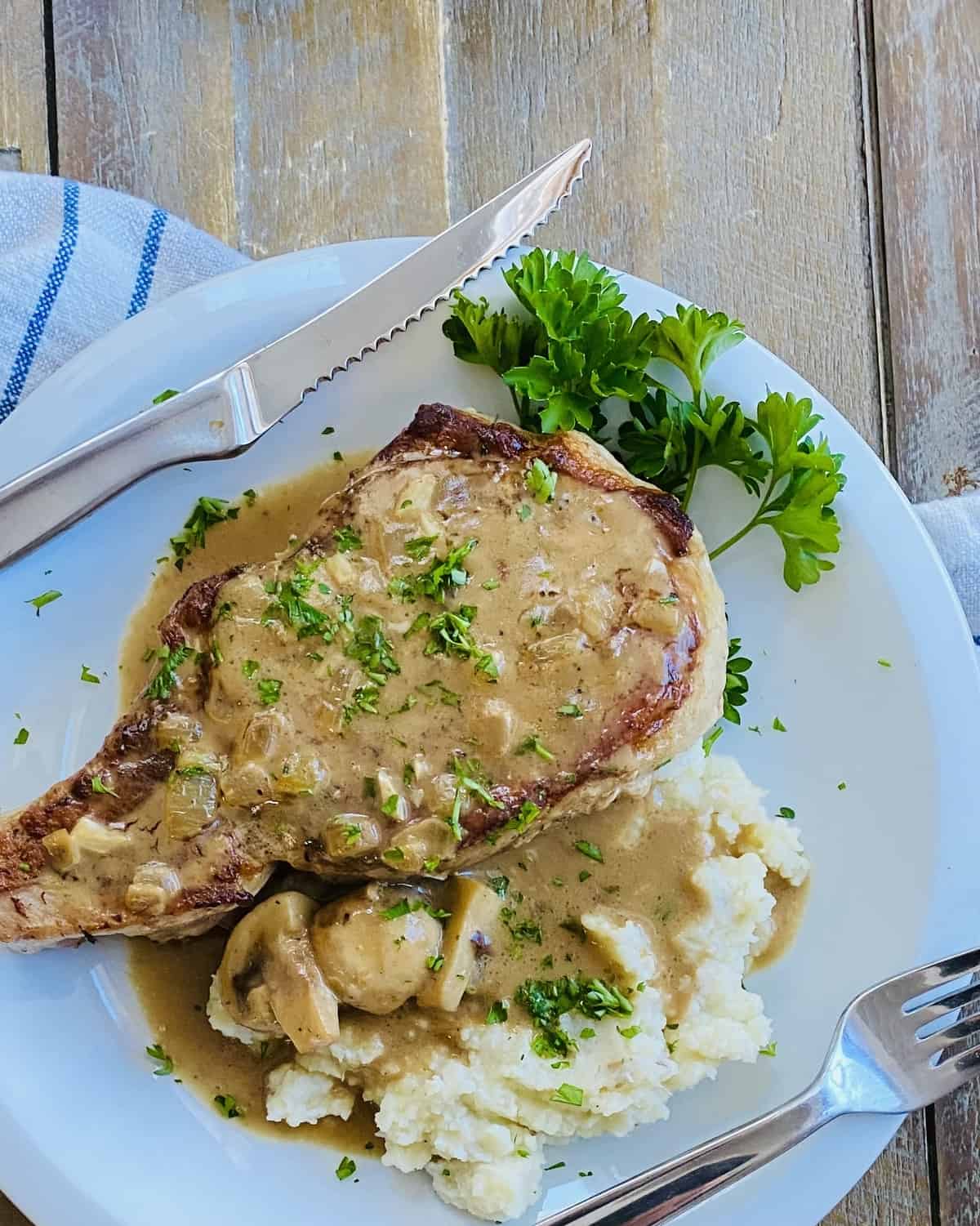 A bone-in pork chop with mushroom gravy over mashed potatoes.