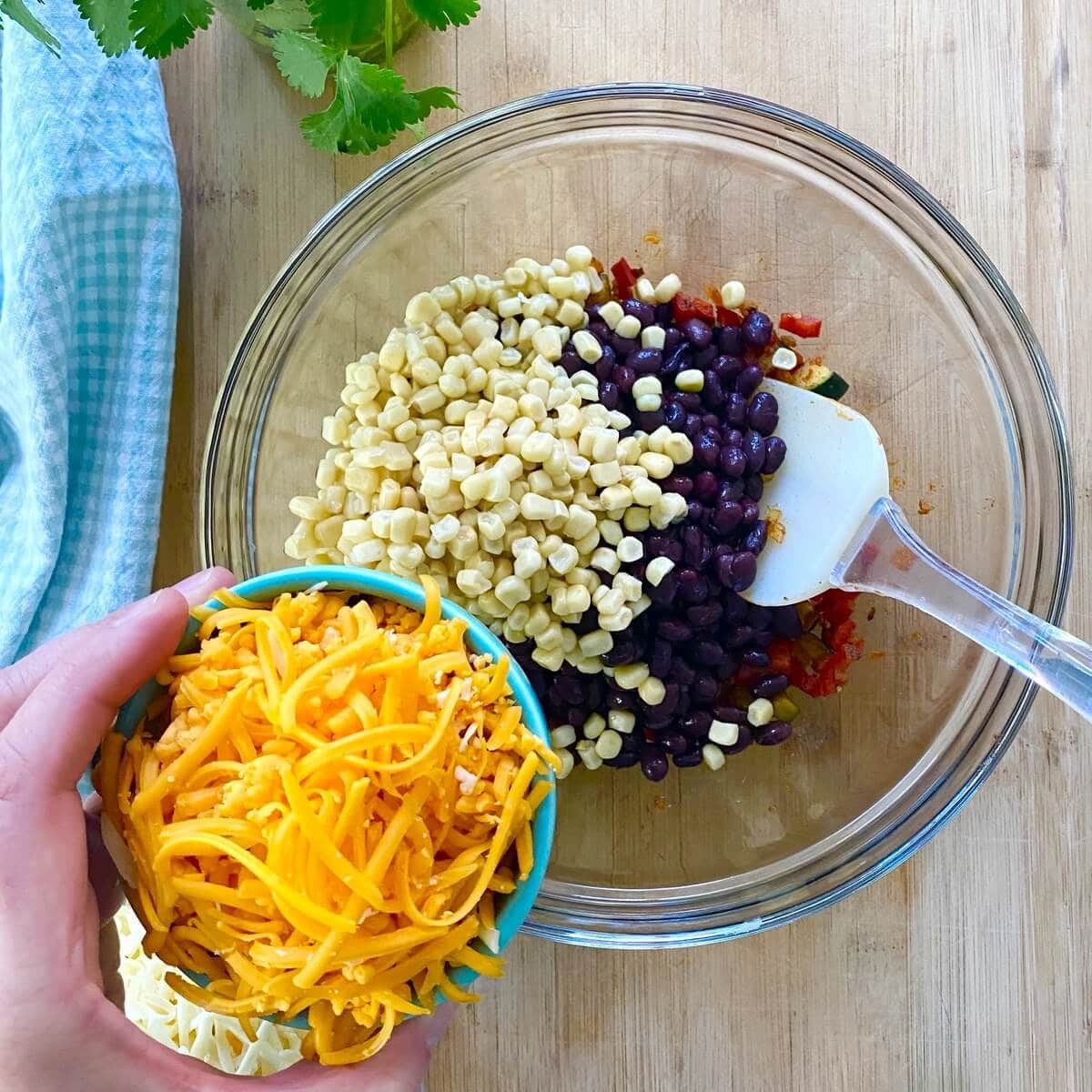 Shredded cheese, corn and black beans in a bowl.