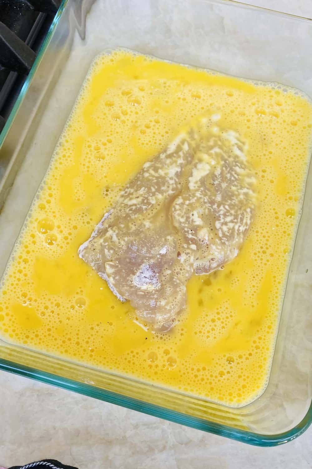 Dipping floured chicken in egg wash.
