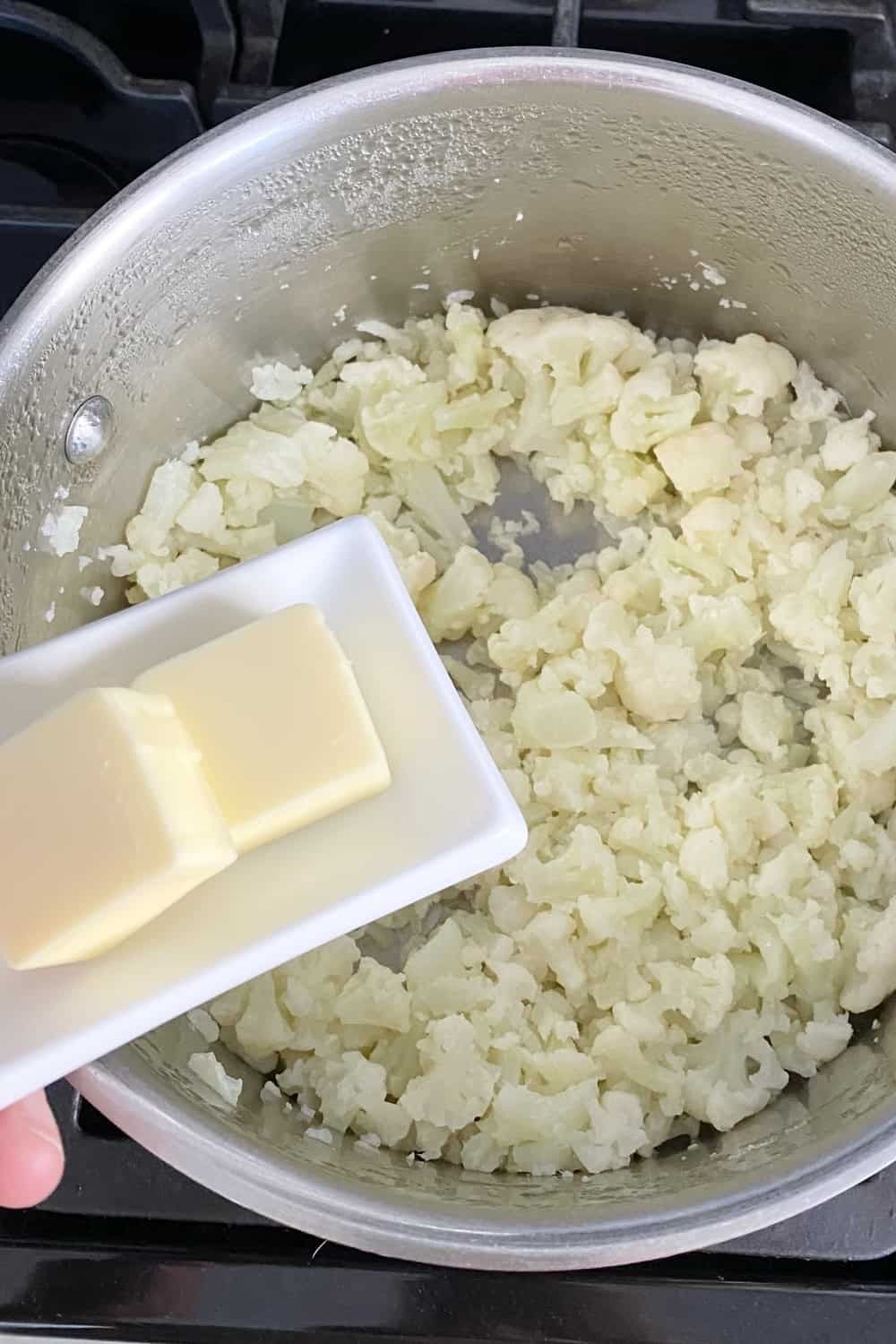 Adding butter to make mashed cauliflower.