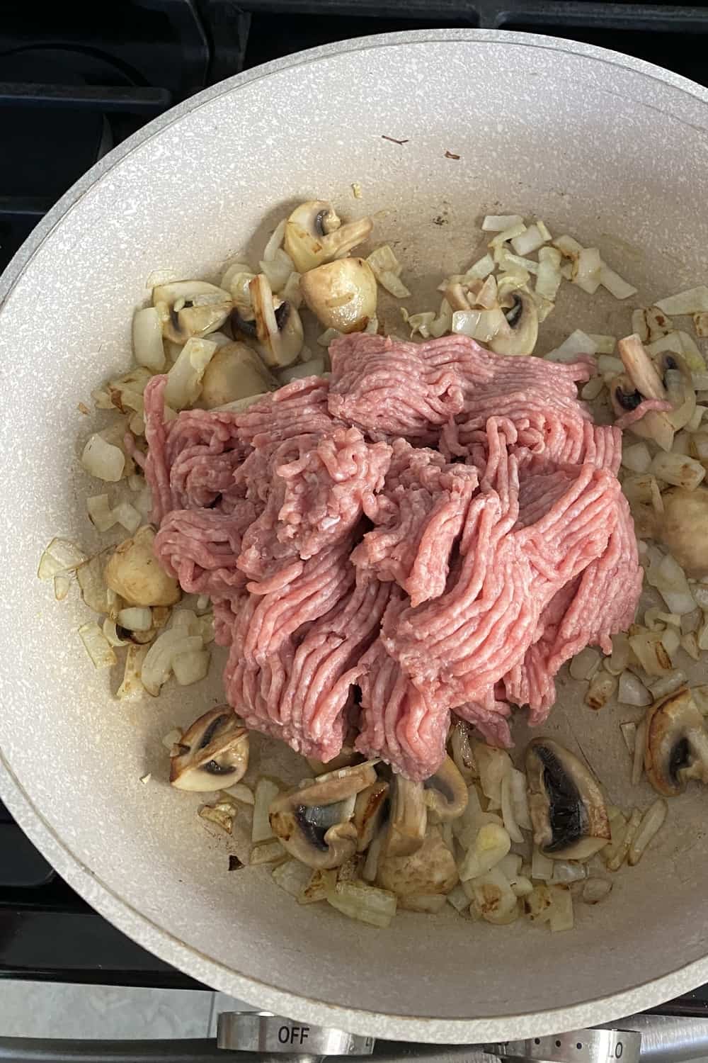 Sauteed mushrooms and onions with ground turkey in a pan.