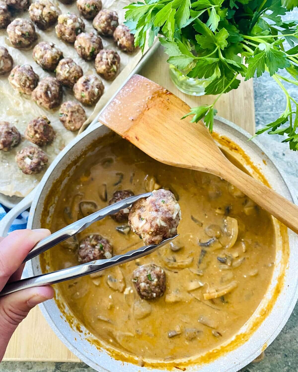 Adding meatballs to stroganoff sauce.