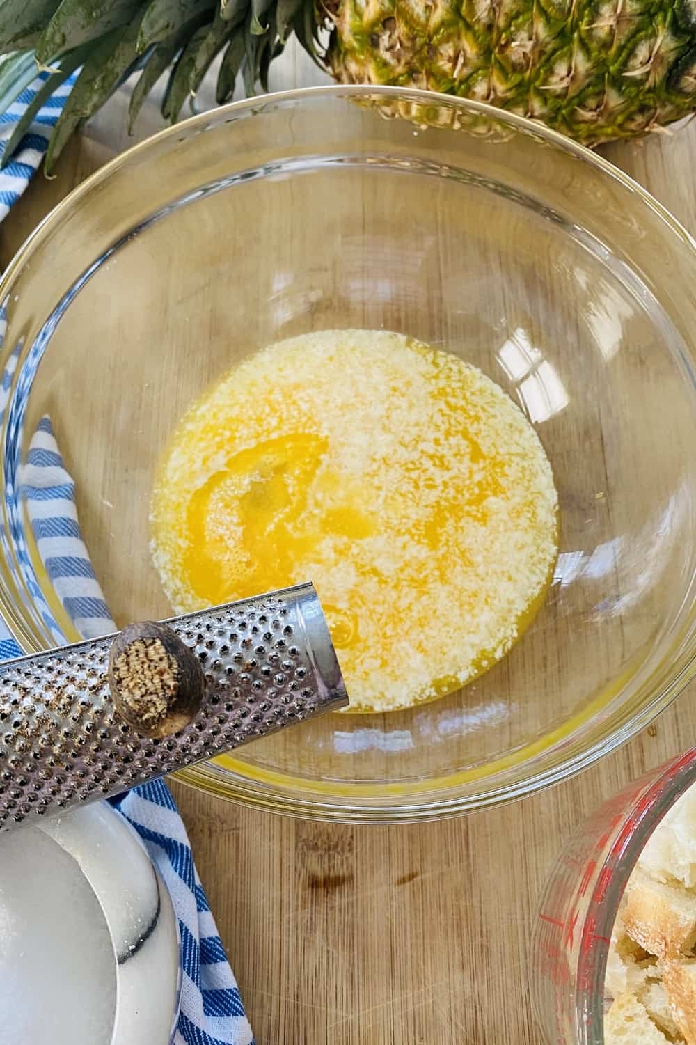Grating nutmeg into a bowl of melted butter.